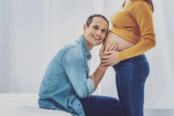 Delighted man putting head on the tummy of his wife — Stock Photo, Image