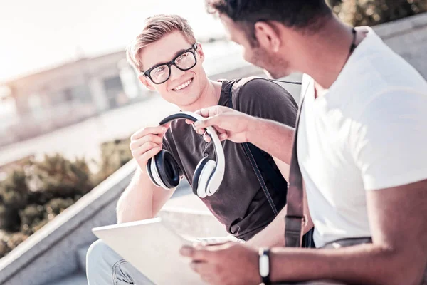 Positiver Student nimmt seinem Freund Kopfhörer ab — Stockfoto