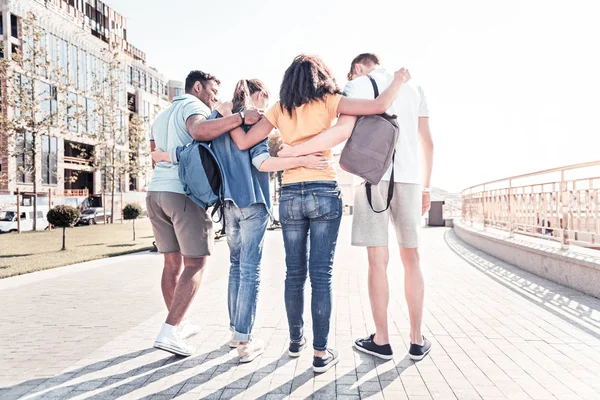 Vista posterior de compañeros de grupo amistosos que de pie juntos — Foto de Stock