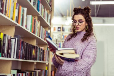 Gerçek açıklama arama. Bir elinde kazık taşırken seçilen kitabın içeriği gözlemleyerek özenli uzun saçlı kız