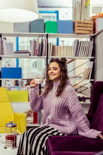 Sonriente dama alegre con falda rayada escalofriante en un sofá de terciopelo — Foto de Stock