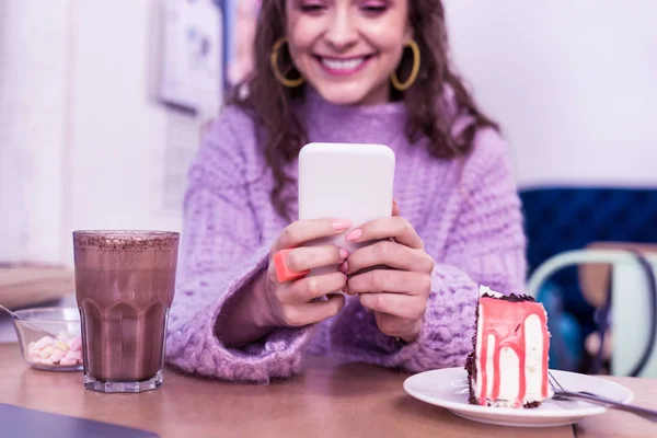 Sorridente signora positiva controllando i suoi social media mentre seduto nel caffè — Foto Stock