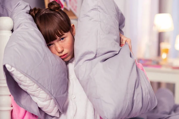 Negative delighted teenager holding two soft pillows — Stock Photo, Image