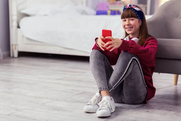 Relaxed schoolgirl crossing legs while sitting on floor — Stock Photo, Image