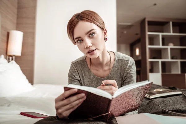 Blonde-haired woman making notes in her planner while on business trip