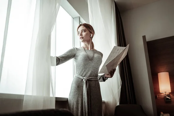 Kobieta patrząc w okno sprawdzania pogody noszenie sukienka — Zdjęcie stockowe