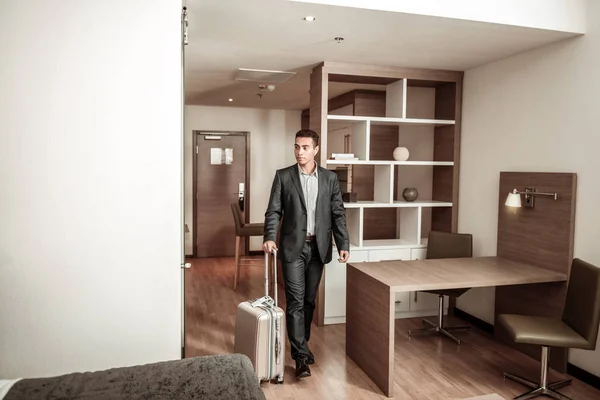 Young businessman entering hotel room with his luggage