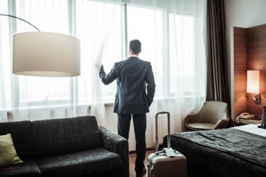 Pencere otelinde bakarak koyu takım elbise giyen işadamı