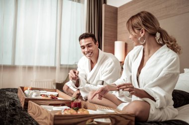 Çift otel odasında kahvaltı keyfi beyaz bornoz giyiyor