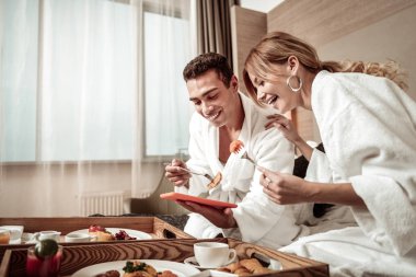 Çift yatakta kahvaltı ve onların gezisi fotoğraflarını izlerken