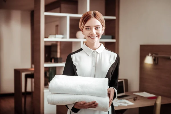 Młody przyjemny hotel blond pokojówka gospodarstwa białe ręczniki — Zdjęcie stockowe