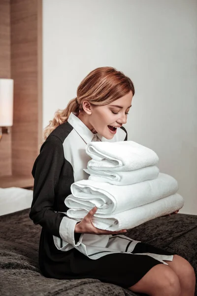 Piękny hotel pokojówka z blondynka kręcone włosy patrząc na ręczniki — Zdjęcie stockowe