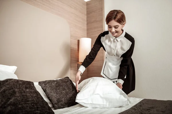 Blond pokojówka uśmiechający się jednocześnie łóżko klientów — Zdjęcie stockowe