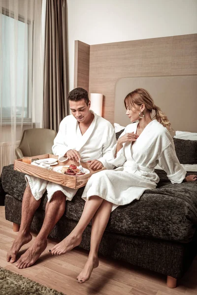 Paar dragen hotel badjassen zittend op hotelbed — Stockfoto