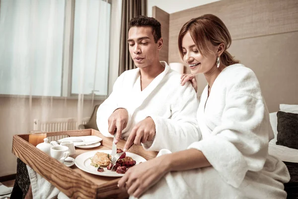 Aantrekkelijke vrouw kijken naar haar mooie man heerlijk ontbijten — Stockfoto