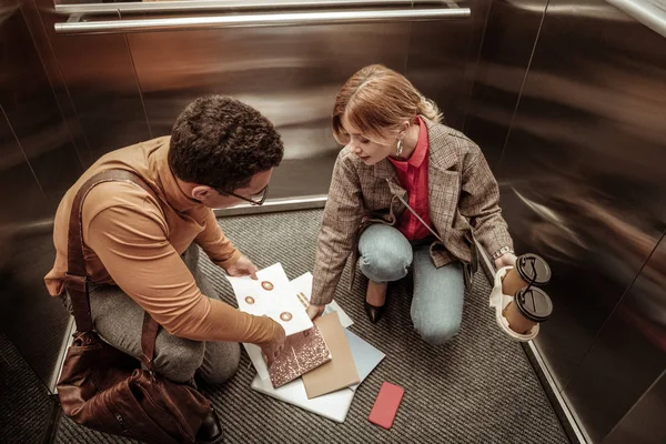 Unaufmerksame Frau wirft Unterlagen im Fahrstuhl auf den Boden — Stockfoto