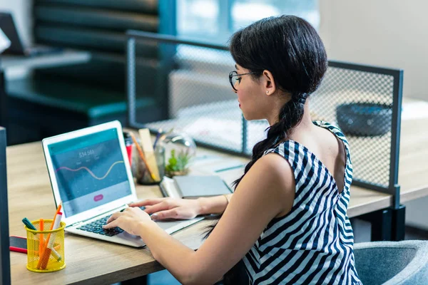 Konzentriertes langhaariges Mädchen sitzt an ihrem Arbeitsplatz — Stockfoto