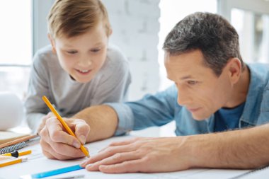 Onun babası çizmek bir plan izlerken meraklı çocuk