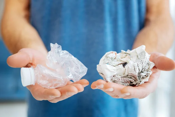 Jeune homme posant avec bouteille en plastique et journal froissé — Photo