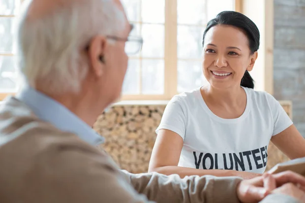 Aangename vrijwilligers en senior man boek bespreken — Stockfoto