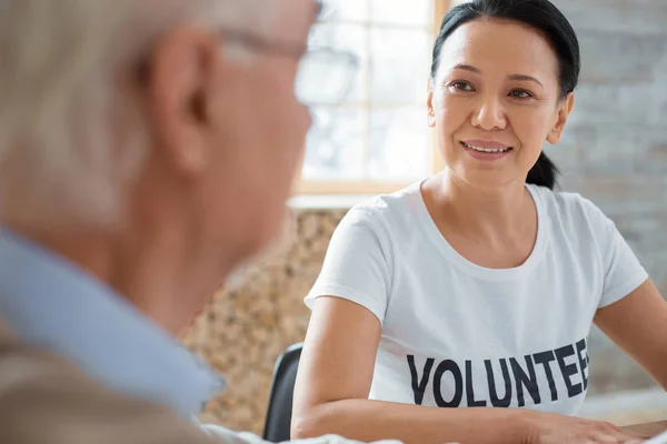 Charmante vrijwilligers en senior man praten — Stockfoto