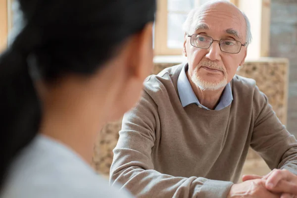 Volontär och allvarliga senior man har konversation — Stockfoto