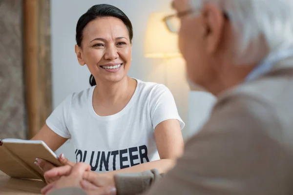 Voluntario alegre comunicarse con el hombre mayor — Foto de Stock