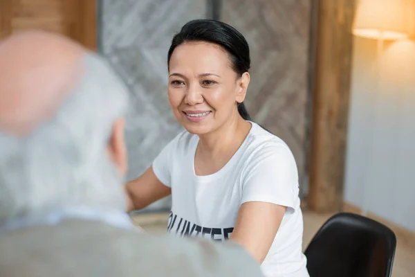 Jovial vrijwilligers vergadering met senior man — Stockfoto