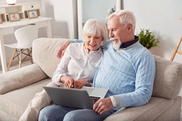 Aangename bejaarde echtpaar kiezen nieuwe laptop in de online winkel — Stockfoto