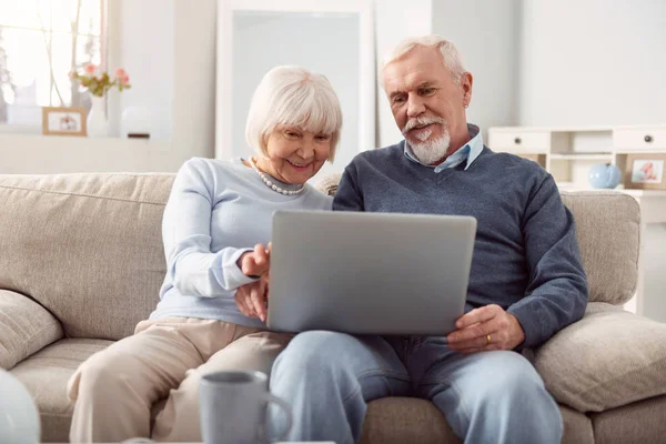 Agradable pareja de personas mayores navegar por Internet en el ordenador portátil juntos — Foto de Stock