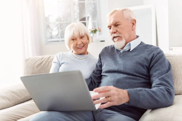 Agradable pareja de ancianos desplazamiento de noticias en el ordenador portátil — Foto de Stock