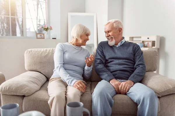 Preciosa pareja de ancianos bromeando mientras están sentados en el sofá — Foto de Stock
