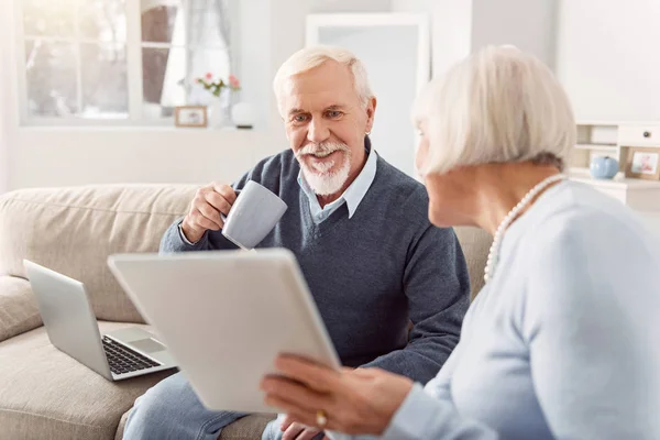 Pleasant senior man reading article his wife showing him — Stock Photo, Image