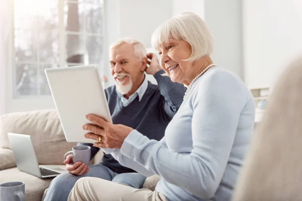 Vrolijke senior man en vrouw die kijken naar video op Tablet PC — Stockfoto