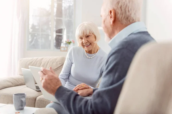 Optimistisches Senioren-Paar schaut sich Enkelkinder-Fotos auf Tablet an — Stockfoto