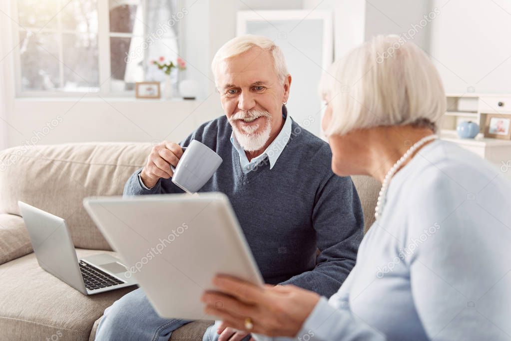 Pleasant senior man reading article his wife showing him