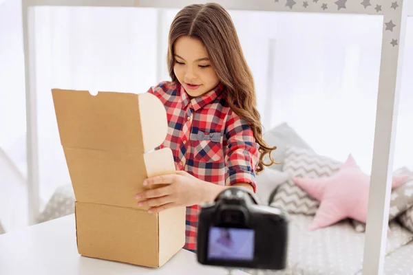 Chica encantadora abriendo una caja mientras graba un vlog — Foto de Stock