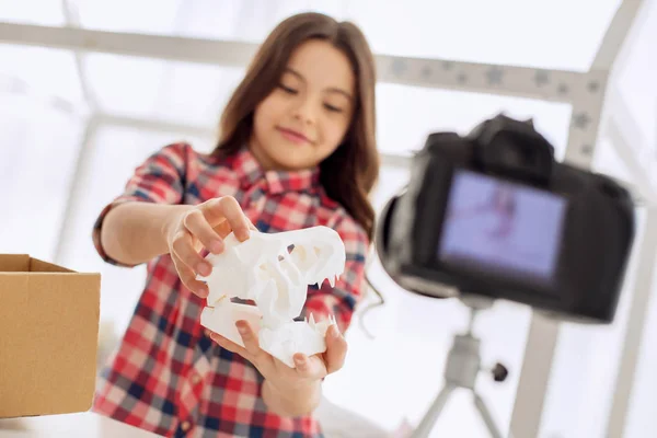 Chica optimista mostrando modelo de cráneo de dinosaurio a la cámara — Foto de Stock