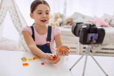 Neşeli kız kamera için gummies avuç gösterilen
