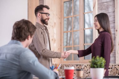 Toplantı iş başında. Ofiste ayakta ve birbirlerini tebrik ederken el sallayarak neşeli pozitif güzel insanlar