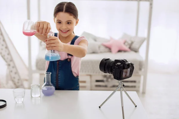 Chica alegre mostrando cómo los colores cambian en los frascos químicos — Foto de Stock
