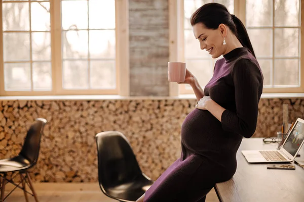 Счастливая беременная женщина разогревается чаем — стоковое фото