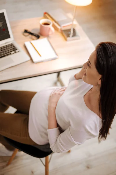 Brunette pregnant woman sitting on chair — Stock Photo, Image