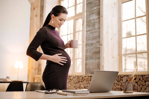 Pleased pregnant businesswoman worrying about baby — Stock Photo, Image