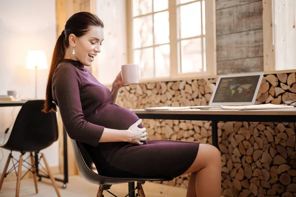 Cheerful pregnant businesswoman feeling baby in tummy — Stock Photo, Image