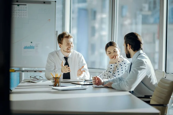 Optimistische Kollegen scherzen beim morgendlichen Briefing — Stockfoto