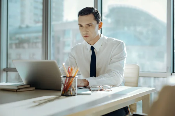 Guapo joven que se centra en el trabajo en el ordenador portátil — Foto de Stock