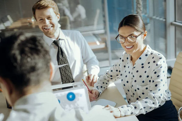 Vrolijke kantoorpersoneel glimlachen terwijl u luistert naar hun collega praten — Stockfoto