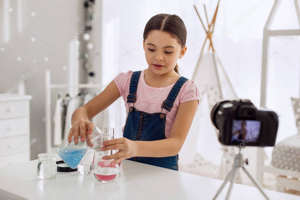 Pleasant girl showing how to mix chemicals correctly