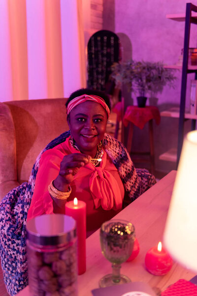African american plump fortune-teller in ethnic adornments holding a burning match